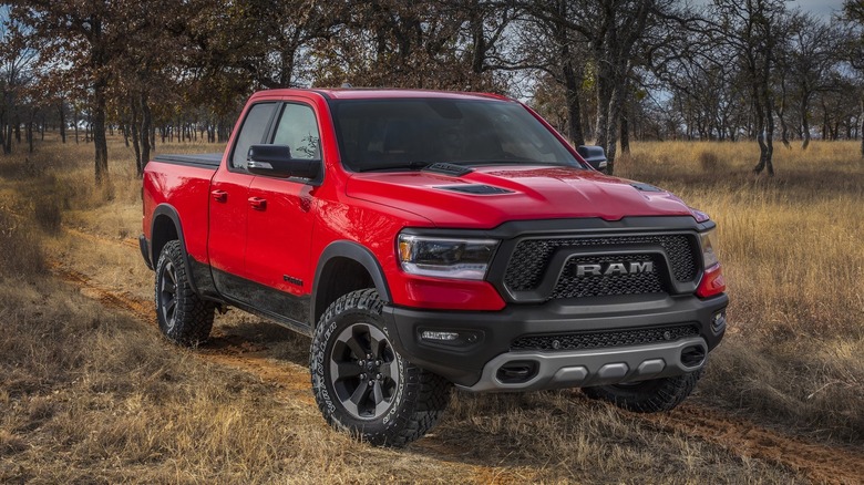 A red Dodge RAM 1500 parked on yellow grass fields with trees in the background.