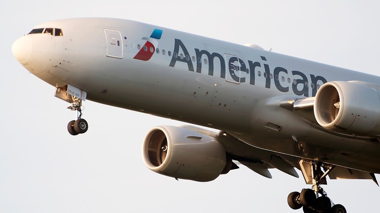 White American Airlines Boeing 777 landing with its two jets and landing gear in frame