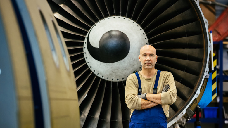 Aircraft mechanic standing near jet engine with a comma design