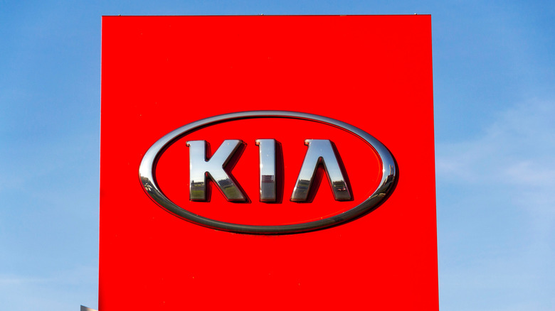 Old Kia logo showing the name in block letters surrounded by a red oval on a dealership building.