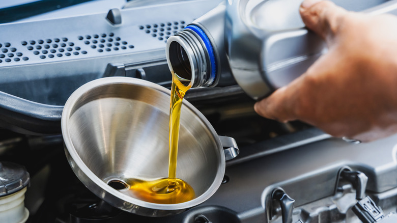 Close-up of person pouring engine oil into funnel