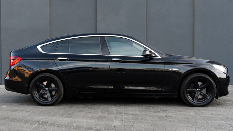 Side view of a predominantly black four-door sedan. with chrome window trim.