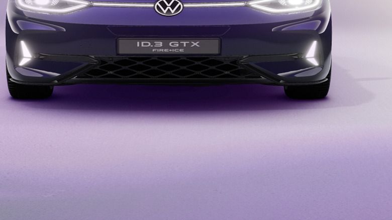A front-on view of a dark purple VW with glowing lights accentuating its headlamps, badge, and hood.