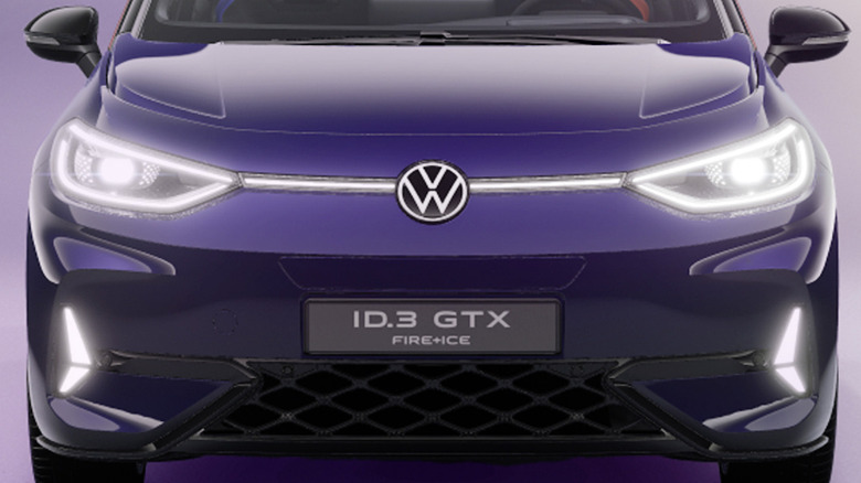 A front-on view of a dark purple VW with glowing lights accentuating its headlamps, badge, and hood.