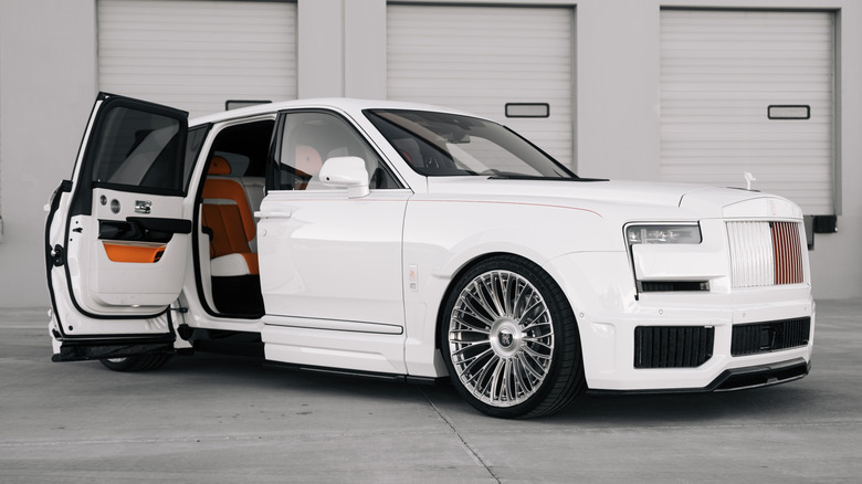 A white Rolls Royce Cullinan with rear coach door open.