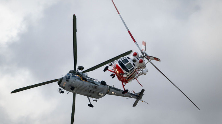 Two helicopter flying close to one another banking right and left