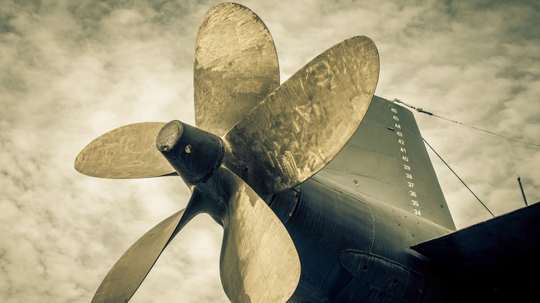 Close up of an 5-bladed submarine propeller against a cloudy sky.
