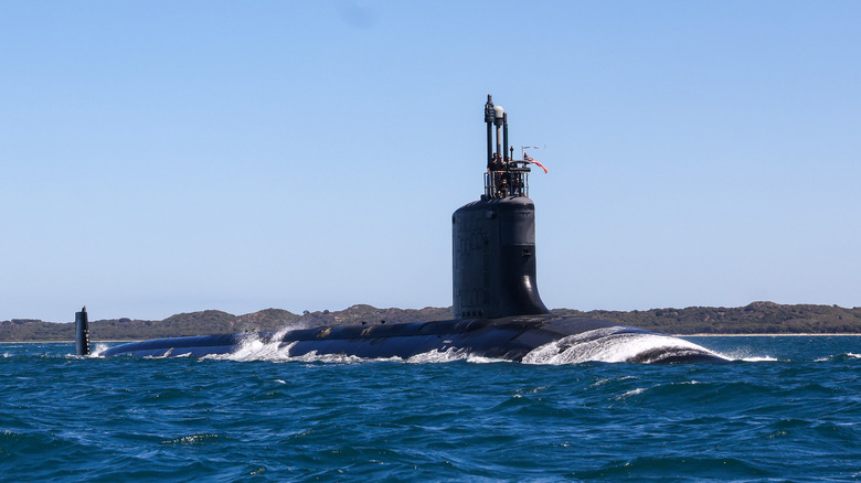 A submarine partially submerged moving through the ocean.