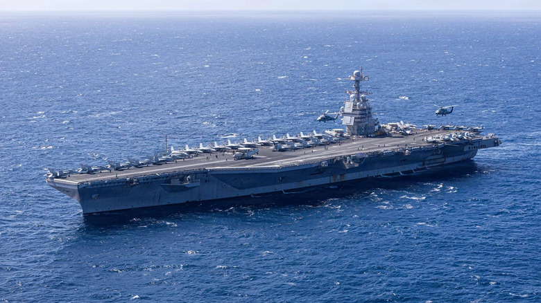 USS Gerald Ford in Caribbean sea with helicopters doing ceremonial flyover