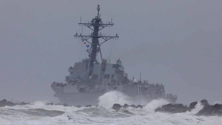 navy ship close to shor and heading out to sea on a stormy day