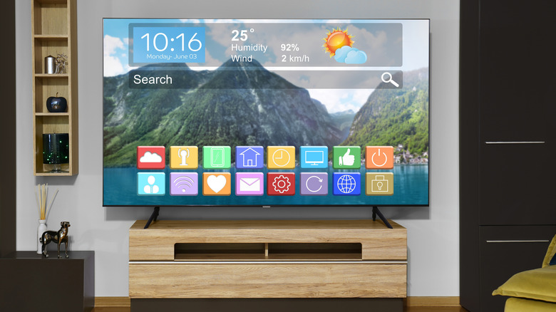 Hand holding remote with smart TV in background