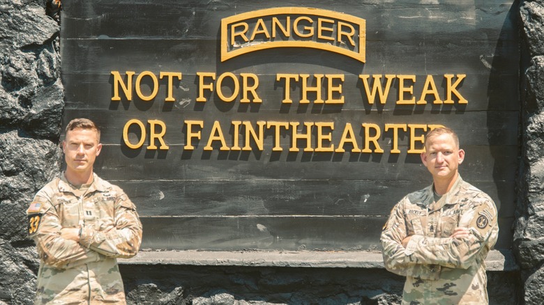 Two soldiers standing proudly in front of the Ranger sign at Fort Benning, Georgia