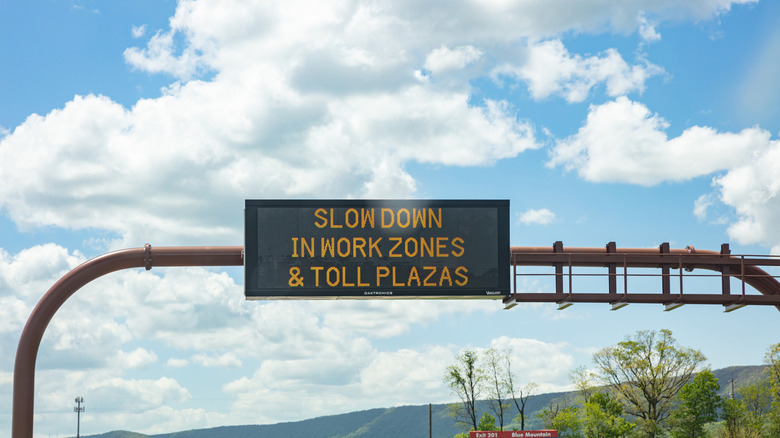 Electronic road sign reading "Slow Down in Work Zones and Toll Plazas"