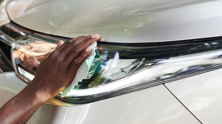 Person wiping headlights with a cloth