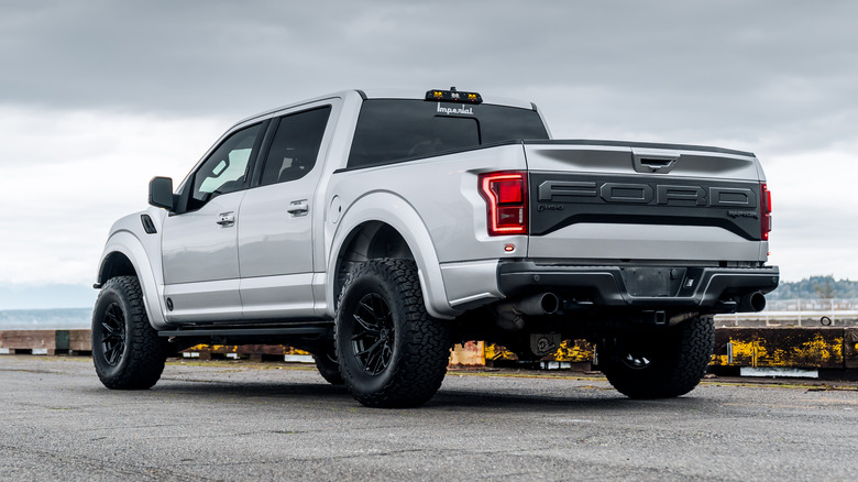A rear quarter view of a white Ford truck parked at the side of the road.