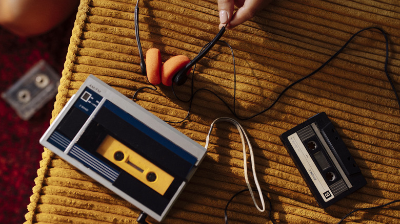 A portable cassette player, cassette, and headphones, on yellow fabric