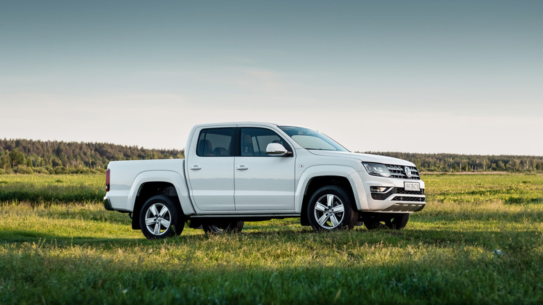 A white Volkswagen Amarok parked in a green field