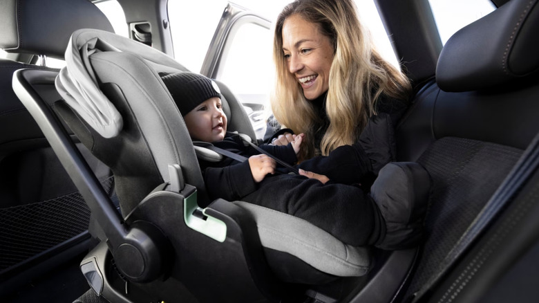 Mother putting child in rear facing baby seat