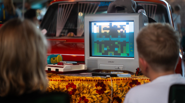 Two kids playing retro games on a CRT TV.