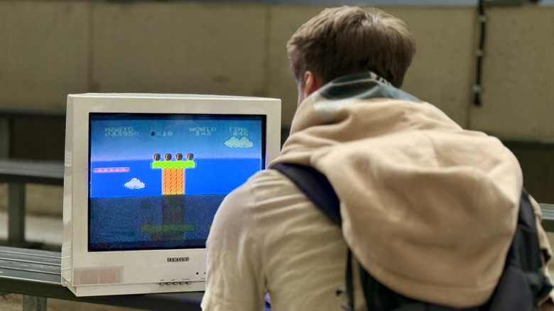 A young man playing Super Mario Bros. on a CRT TV.