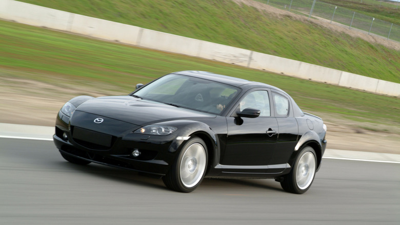 A black 2004 Mazda RX-8 driving on track