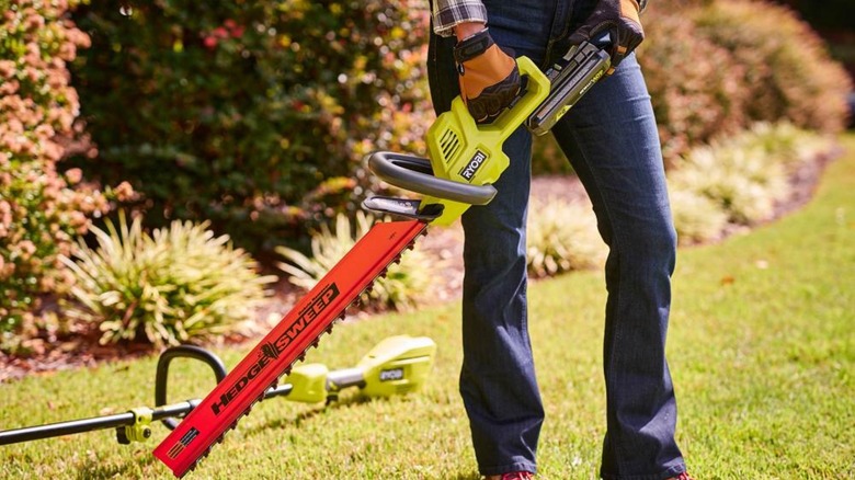 Person using ryobi hedge trimmer.