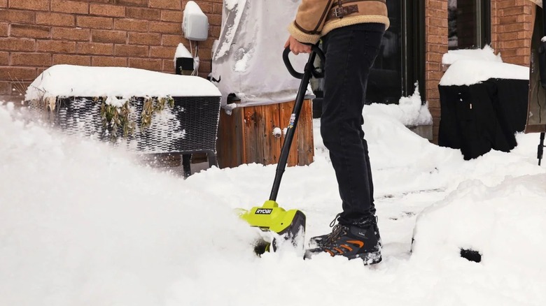 A person using a Ryobi snow shovel outside.