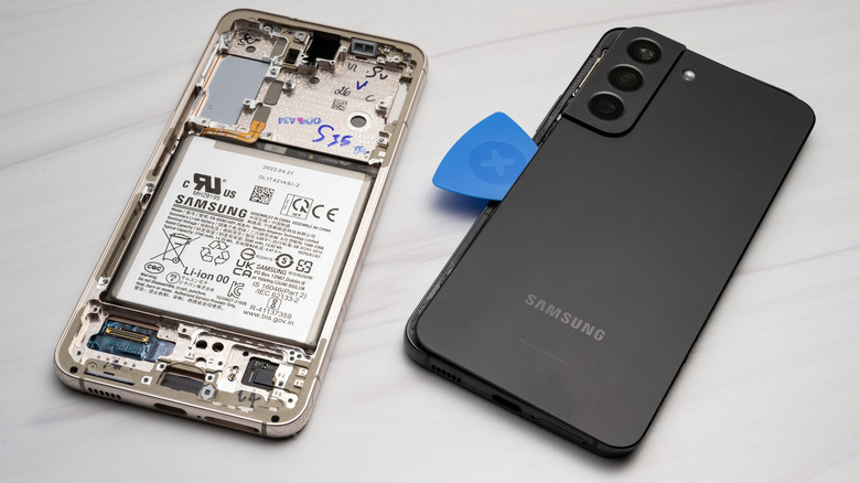 An iFixit opening pick is used to remove the back panel of a Samsung S22
