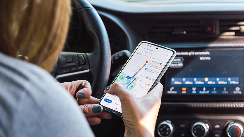 A person using Google Maps on a smartphone in their car.