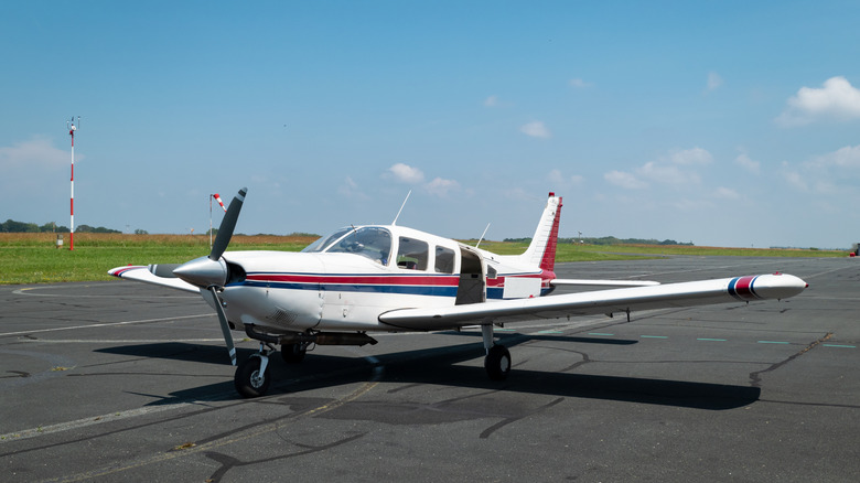 A white propeller plane with blue and red stripes on the runway