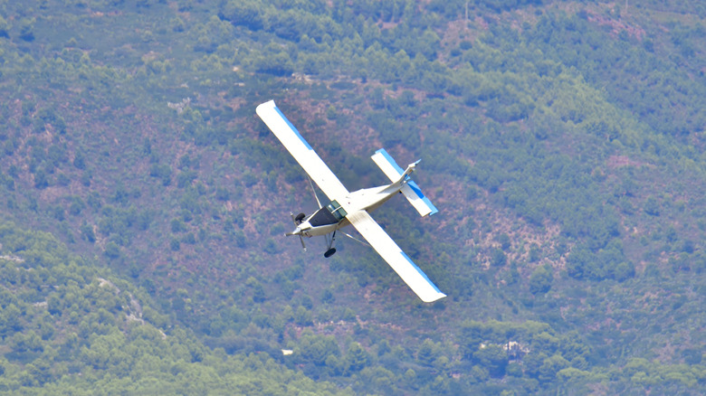 A propeller plane yawing left mid-flight, mountain in the background