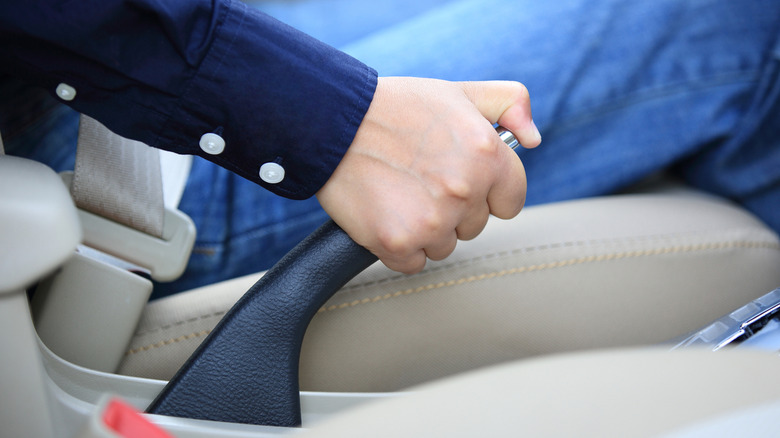 Driver's hand pulling up on manual parking brake