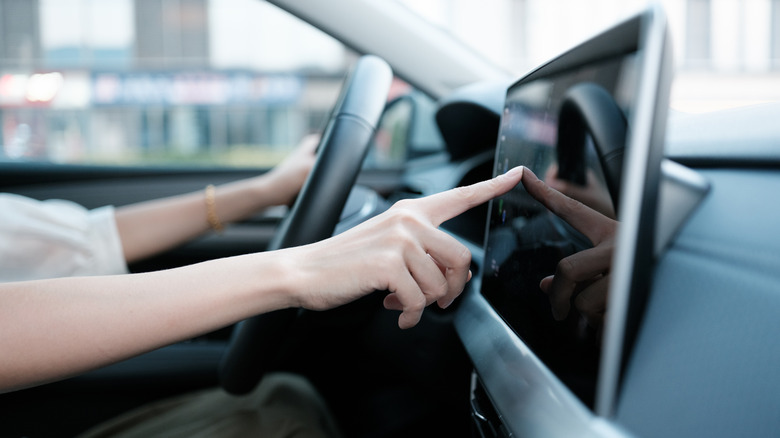 A driver uses a large infotainment touchscreen