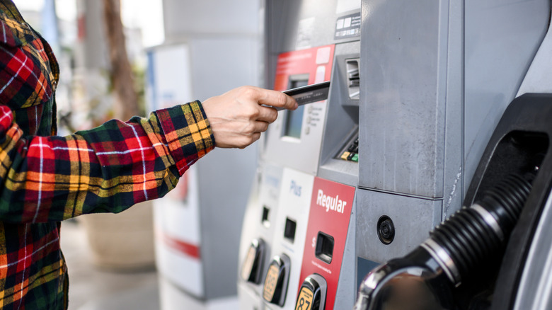 A person about to insert a bank card into a gasoline pump