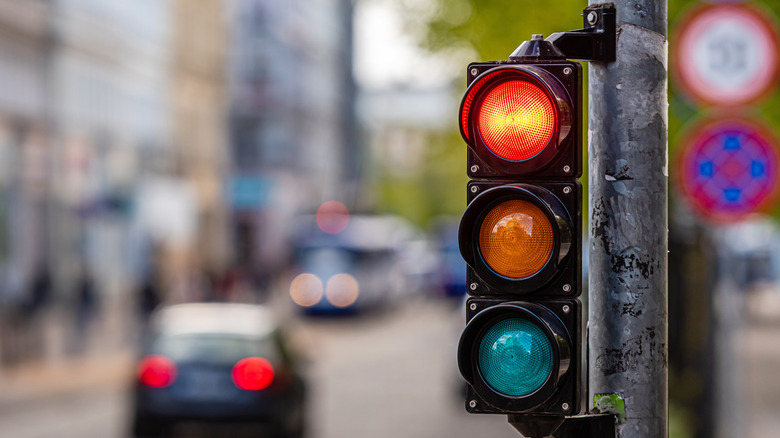 A red traffic light on a busy city street, out of focus cars and public transport in the background