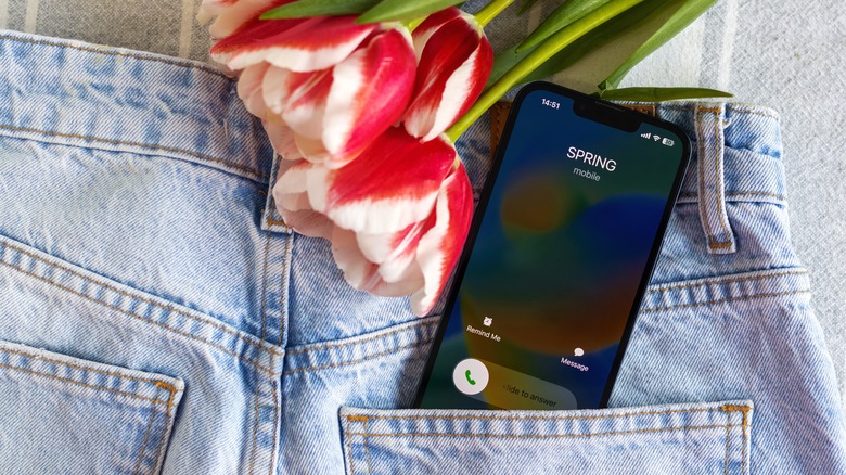 iPhone showing incoming call screen in back pocket of blue jeans with flowers