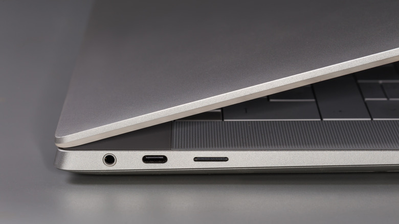 Fragment of side part of the slightly unfolded laptop in the thin silvery case