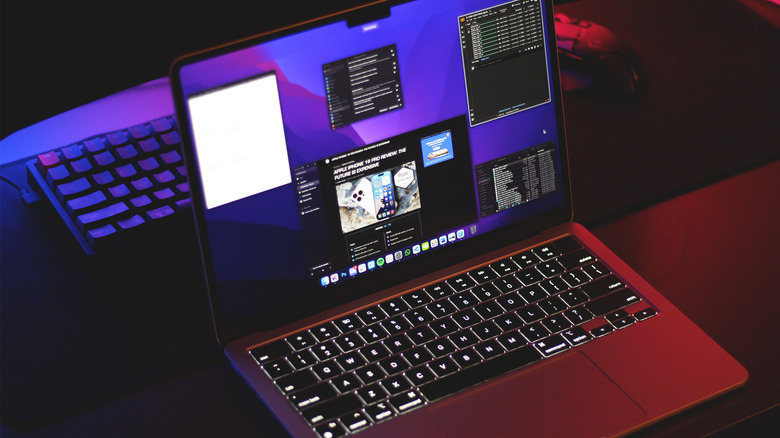 A MacBook with multiple apps open, mechanical keyboard and Logitech G mouse in the background