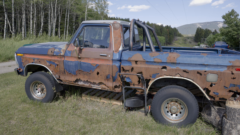 An old and rusted pickup truck in alleyway in forest