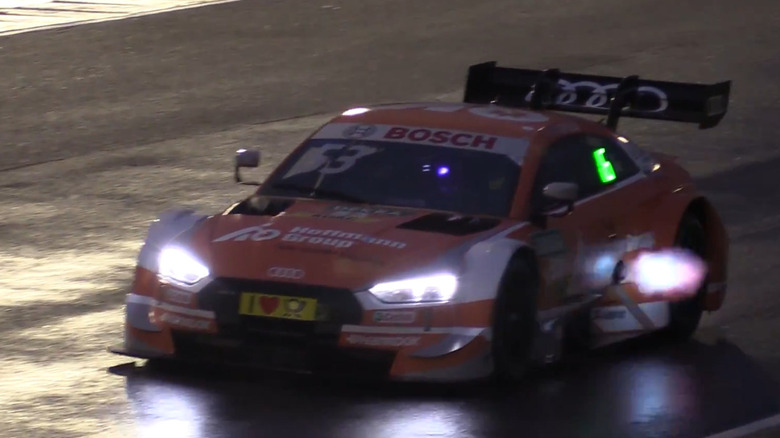 Audi RS5 DTM race car at night with flames emanating from side-mounted exhaust, front-left view
