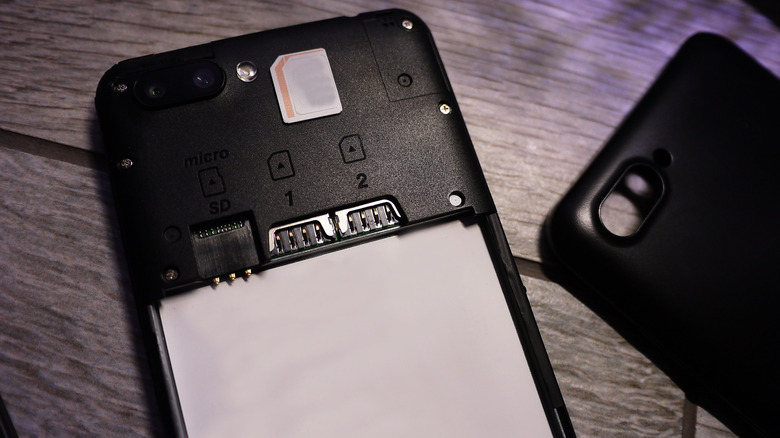 A smartphone with its back panel removed placed on a wooden table