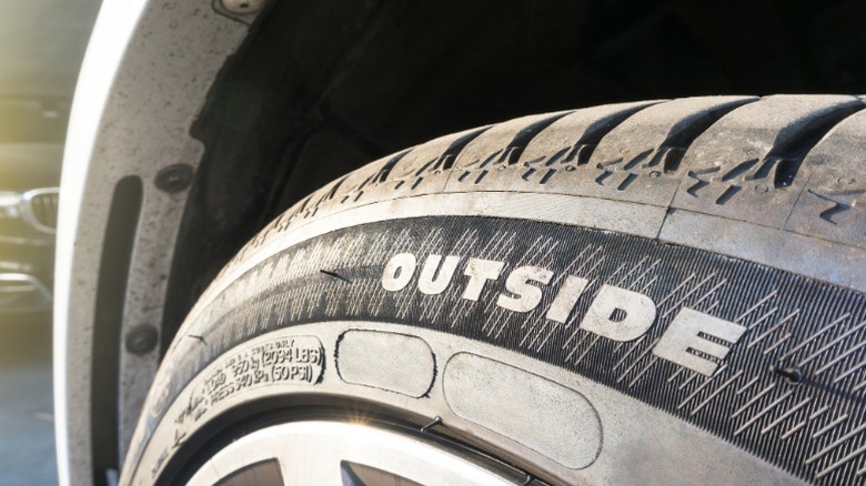A directional car tire with the word outside written on the sidewall