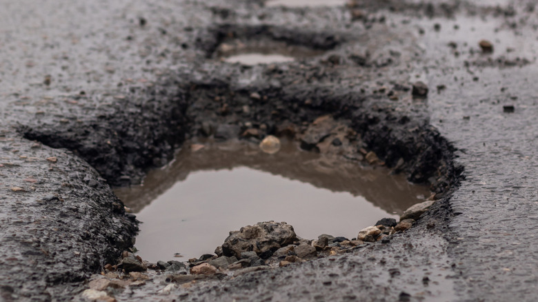 A deep road pothole filled with water.