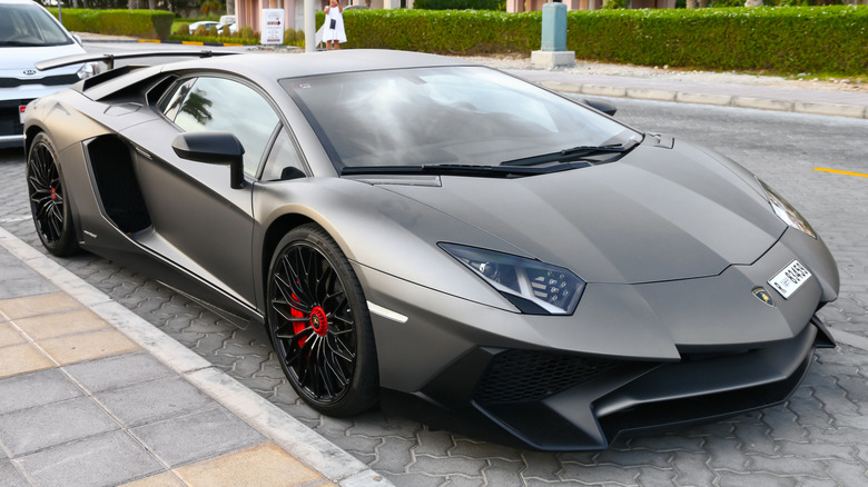 A matte gray Lamborghini Aventador parked on a cobblestone road