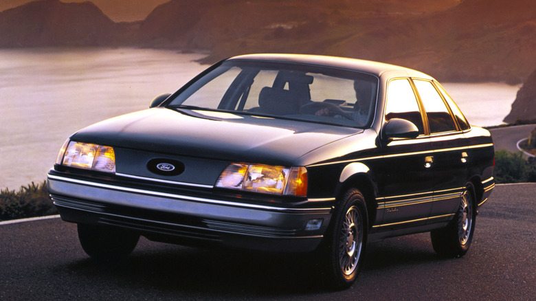 Black 1986 Ford Taurus parked road