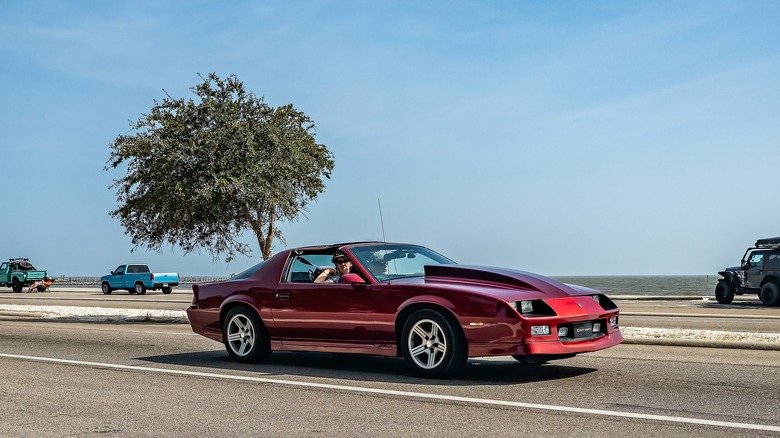 Red 1989 Chevrolet Camaro IROC-Z on coastal highway
