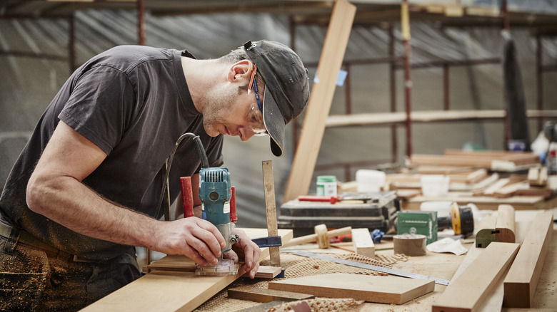 A carpenter using a machine tool on some wood in a workshop