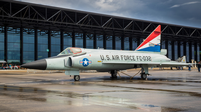 An F-102 Delta Dagger parked on a tarmac outside a hangar