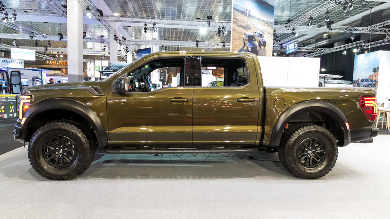 Side view of a metallic green Ford F150 Raptor on display.