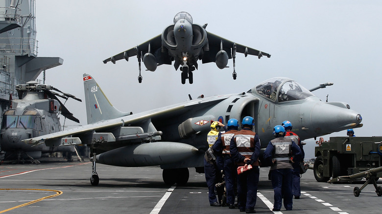 Harrier jet hovers as it lands on the HMS Ark Royal